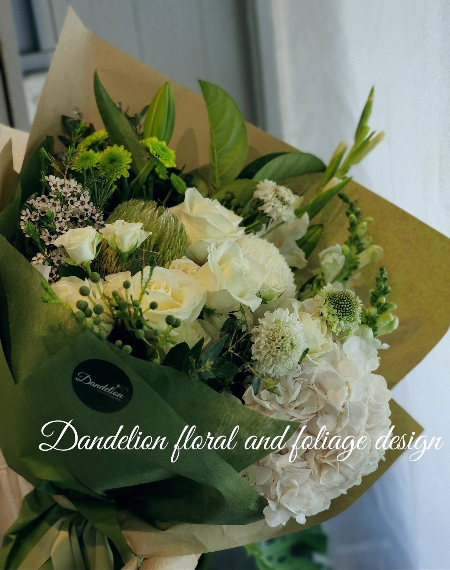 A bouquet of white and green flowers wrapped in green paper.