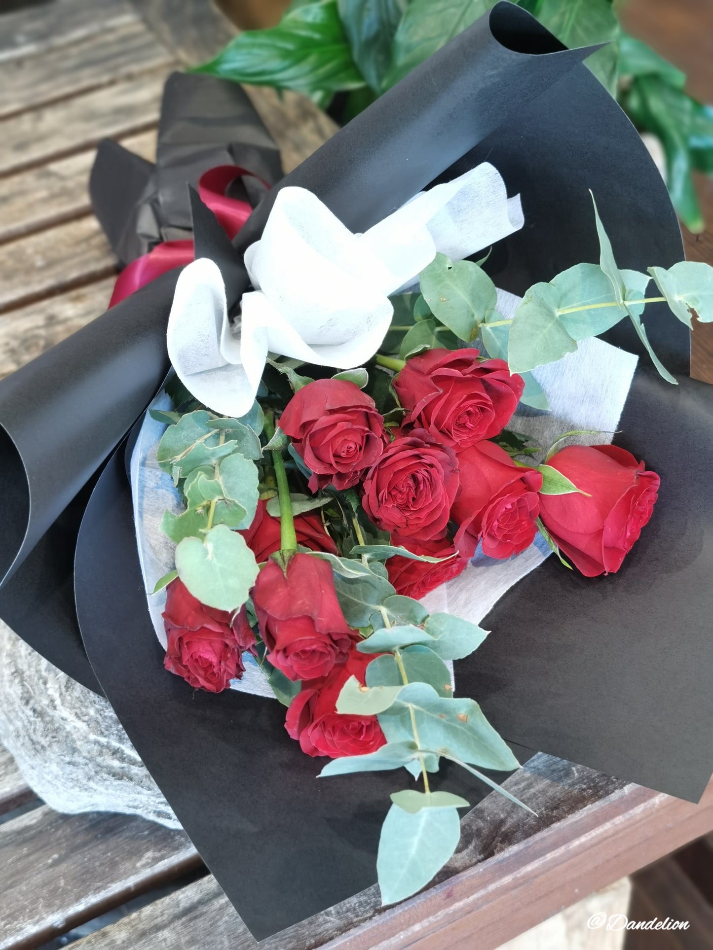 A bouquet of red roses with green foliage, wrapped in a black paper, 40cm premium red roses with seasonal foliage.