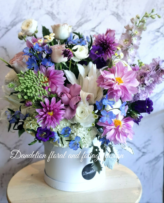 This resplendent selection of blue, mauve and purple flowers artfully arranged into a box arrangement makes an ideal gift for all.