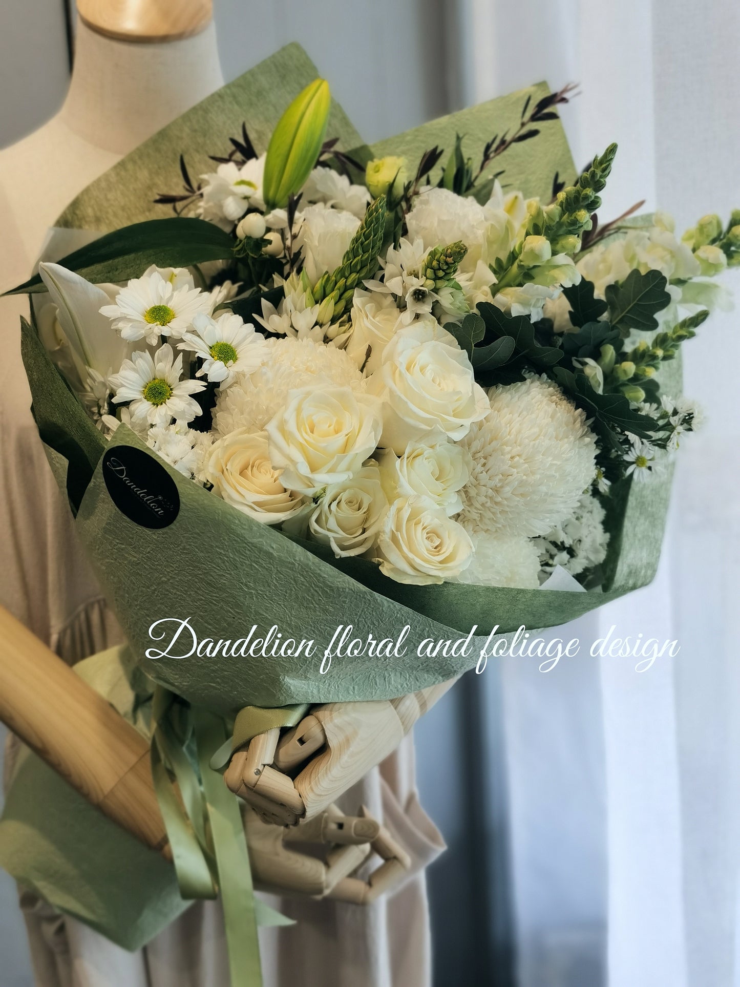 A bouquet of white and green flowers wrapped in green paper.