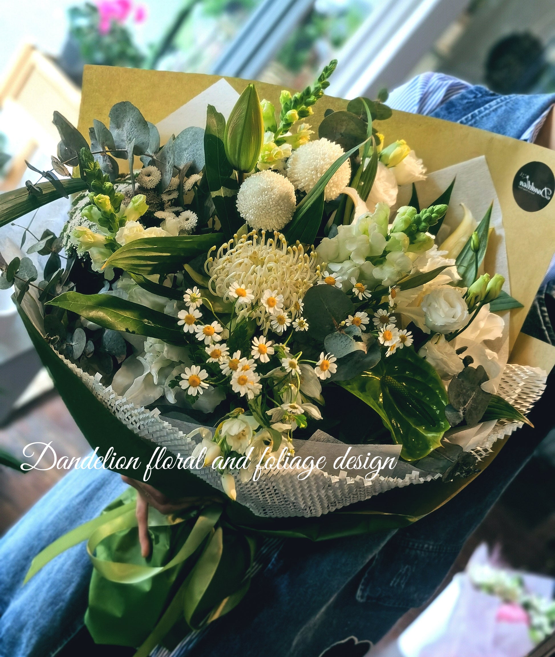 A bouquet of white and green flowers wrapped in green/brown paper. 