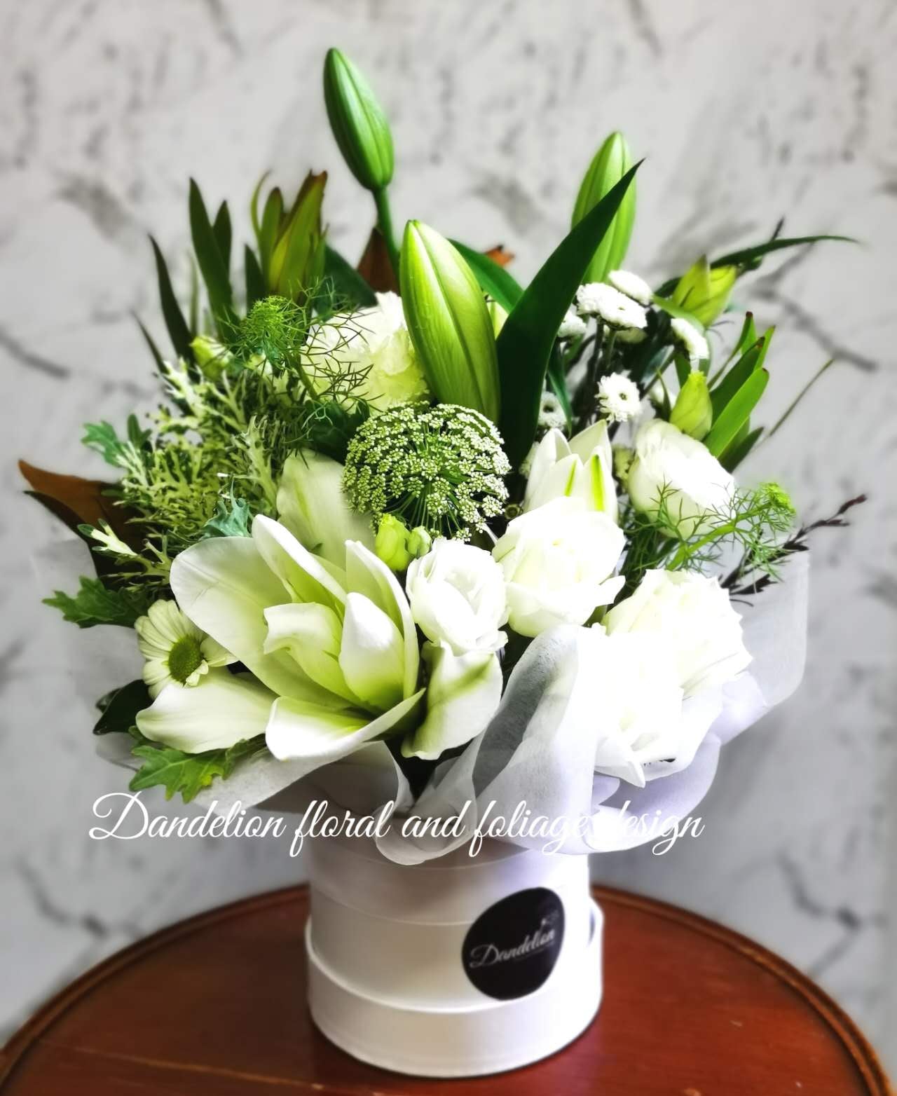 Arrangement of lilies, and other white flowers with greenery in hat box