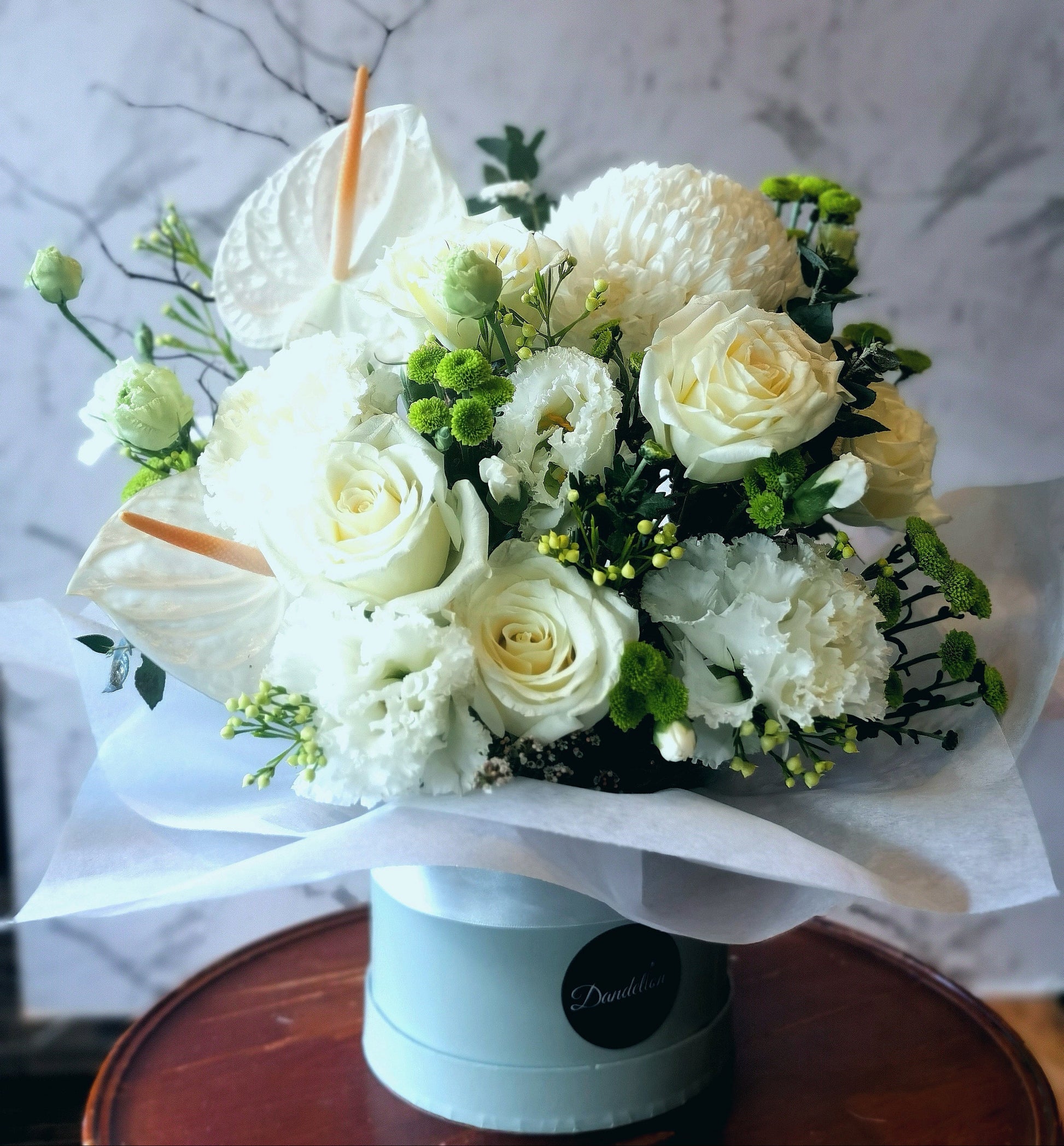 Elegant white and green floral arrangement with seasonal blooms in a classic white hat box.