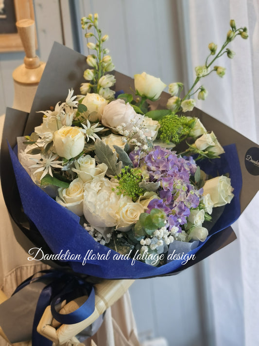 This blue bloom bouquet uses cool tones with seasonal flowers and complimenting greenery. This is a perfect gift to celebrate occasions for baby boy, graduation, birthday, anniversary and more.