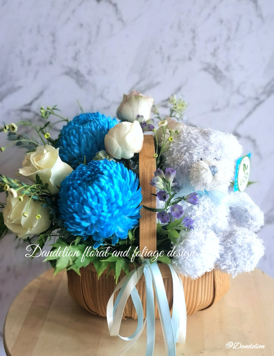 Congratulate new parents or beautify the home with a gorgeous palette of white florals with a touch of blue. For added joy this arrangement includes a fluffy teddy bear. The gift includes seasonal white, blue and green flowers in a basket.