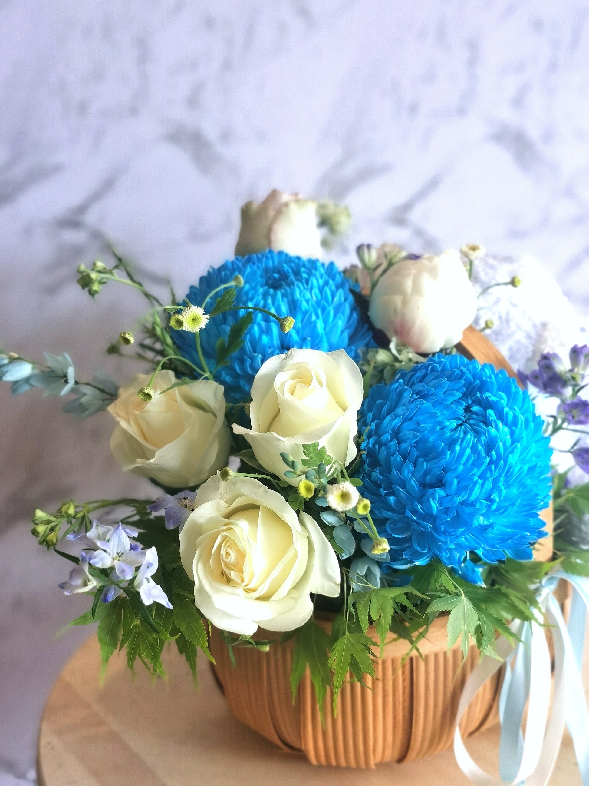 Congratulate new parents or beautify the home with a gorgeous palette of white florals with a touch of blue. For added joy this arrangement includes a fluffy teddy bear. The gift includes seasonal white, blue and green flowers in a basket.