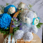 Congratulate new parents or beautify the home with a gorgeous palette of white florals with a touch of blue. For added joy this arrangement includes a fluffy teddy bear. The gift includes seasonal white, blue and green flowers in a basket.
