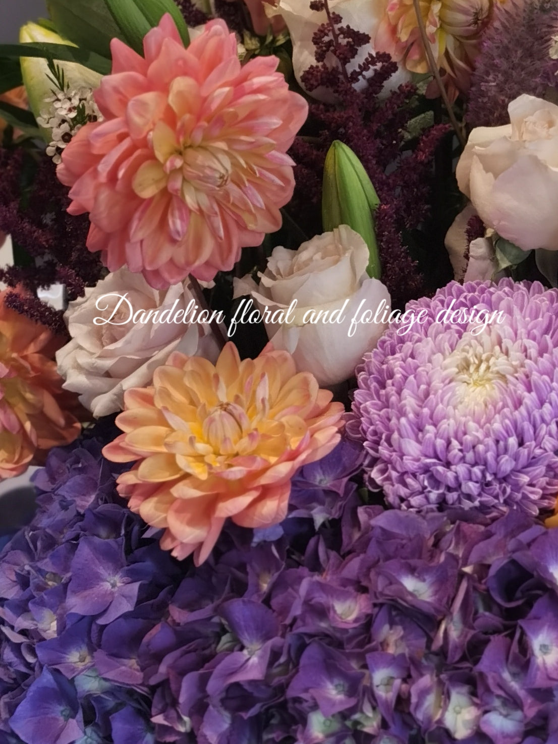 A bright colourful tall hat box arrangement using a mixture of roses, hydrangea, dahlia complimented with other seasonal flowers.
