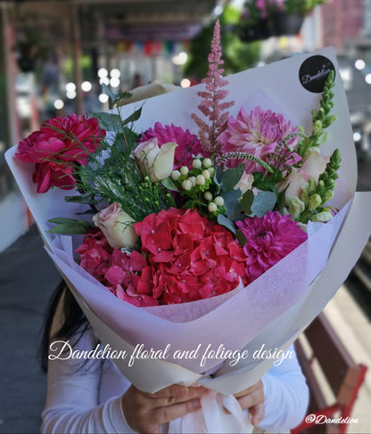 Graduation bouquet in a combination of white, pastel tones using seasonal flowers and greenery.