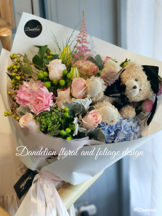 A graduation bouquet featuring a mix of pastel colored flowers and greenery, wrapped with a ribbon, alongside a plush toy bear. Lush bouquet using seasonal blooms in pastel tones complimented with seasonal greenery.
Our Graduation Flowers are the perfect way to send your best wishes and honour their hard work and dedication. With an added special touch our graduation bear - the perfect keepsake.