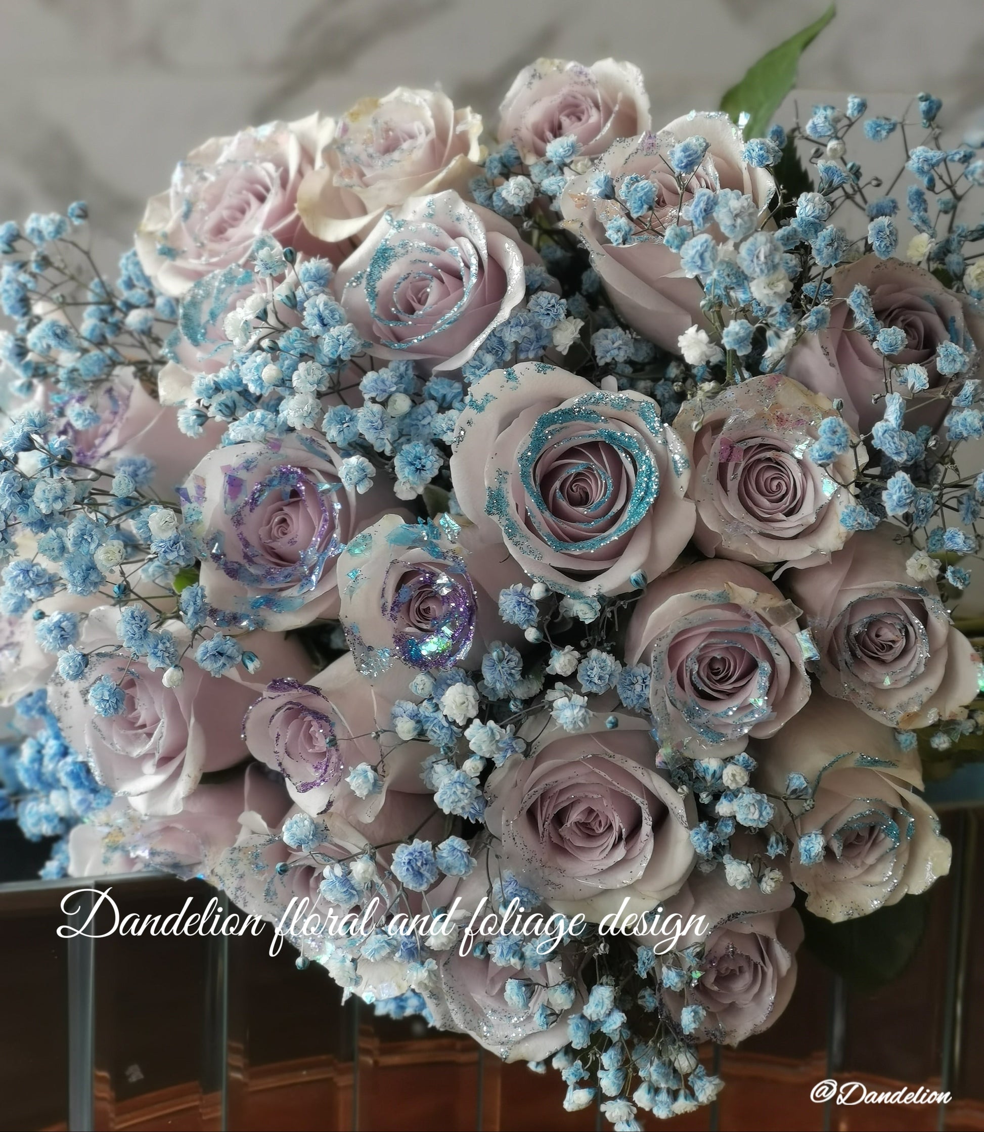 A bouquet of mauve color roses with a shining texture, held by a mannequin. The bouquet features a mix of large and small roses, and is complemented by blue accents in the form of flower beads. 36 stems of&nbsp;premium 40cm mauve colour roses with Shining texture.
Whether impressing a new love, proposing to someone or simply to say "I love you", this&nbsp;special bouquet will take their breath away.
Available in 36 stems(classic), 48 stems(Large) and 60 stems(Deluxe)