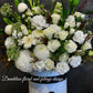 A round tall white hat box filled with white and green flowers, arranged white classic yet in a modern shape. Wedding, engagement or a sad occasion, this arrangement will fulfill what you are in need for.