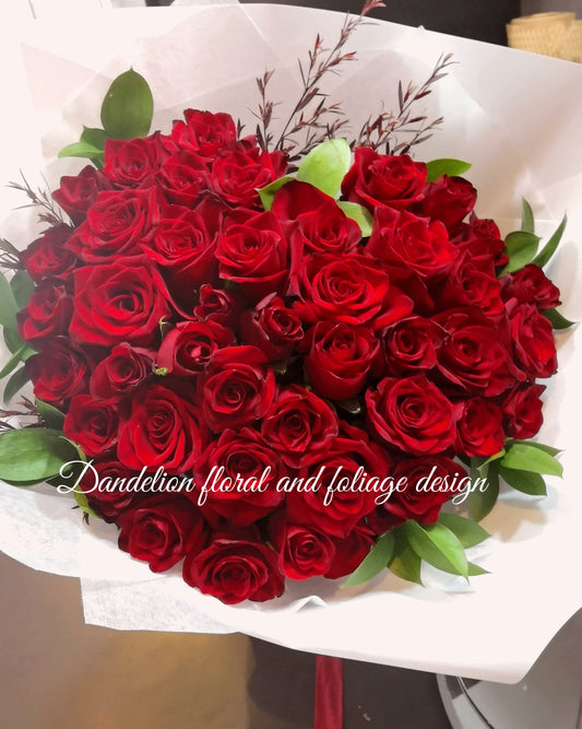 A heart-shaped bouquet of red roses arranged to represent a beating heart, wrapped in white paper with foliage accents. This exquisite heart-shaped rose bouquet is a masterpiece of unique design, crafted to symbolize eternal love. Each rose is meticulously arranged to form a perfect heart, making it a stunning and unforgettable gift for any romantic occasion. Rose length is 40cm or 50cm.