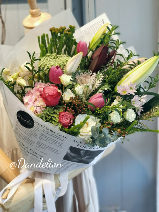 Soft pastel flower bouquet featuring roses and lilies in light pink and cream tones, hand-wrapped