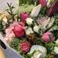 Soft pastel flower bouquet featuring roses and lilies in light pink and cream tones, hand-wrapped