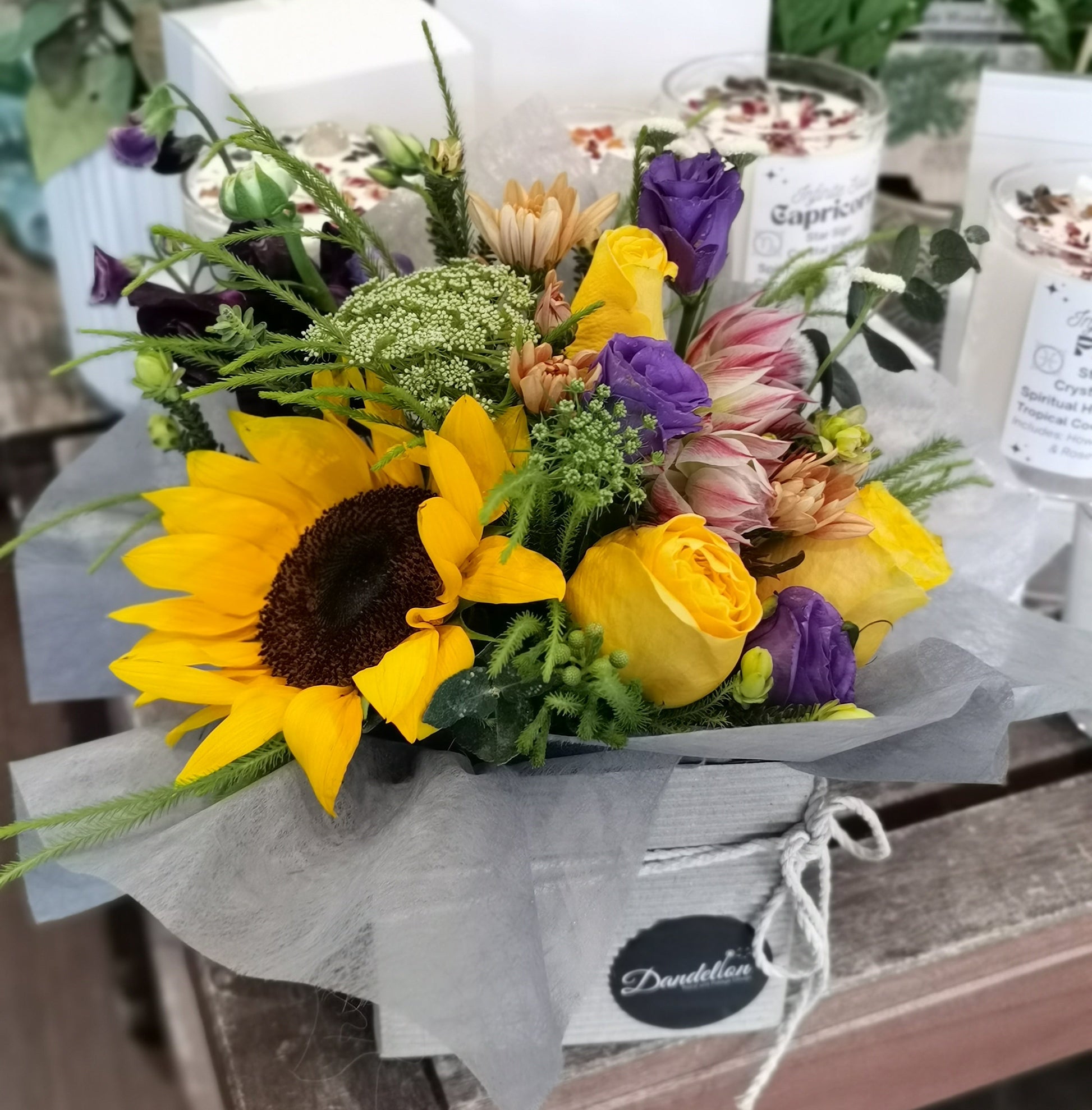 Small arrangement of sunflowers and other yellow/orange flowers in hat box