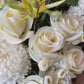 A round tall white hat box filled with white and green flowers, arranged white classic yet in a modern shape. Wedding, engagement or a sad occasion, this arrangement will fulfill what you are in need for.