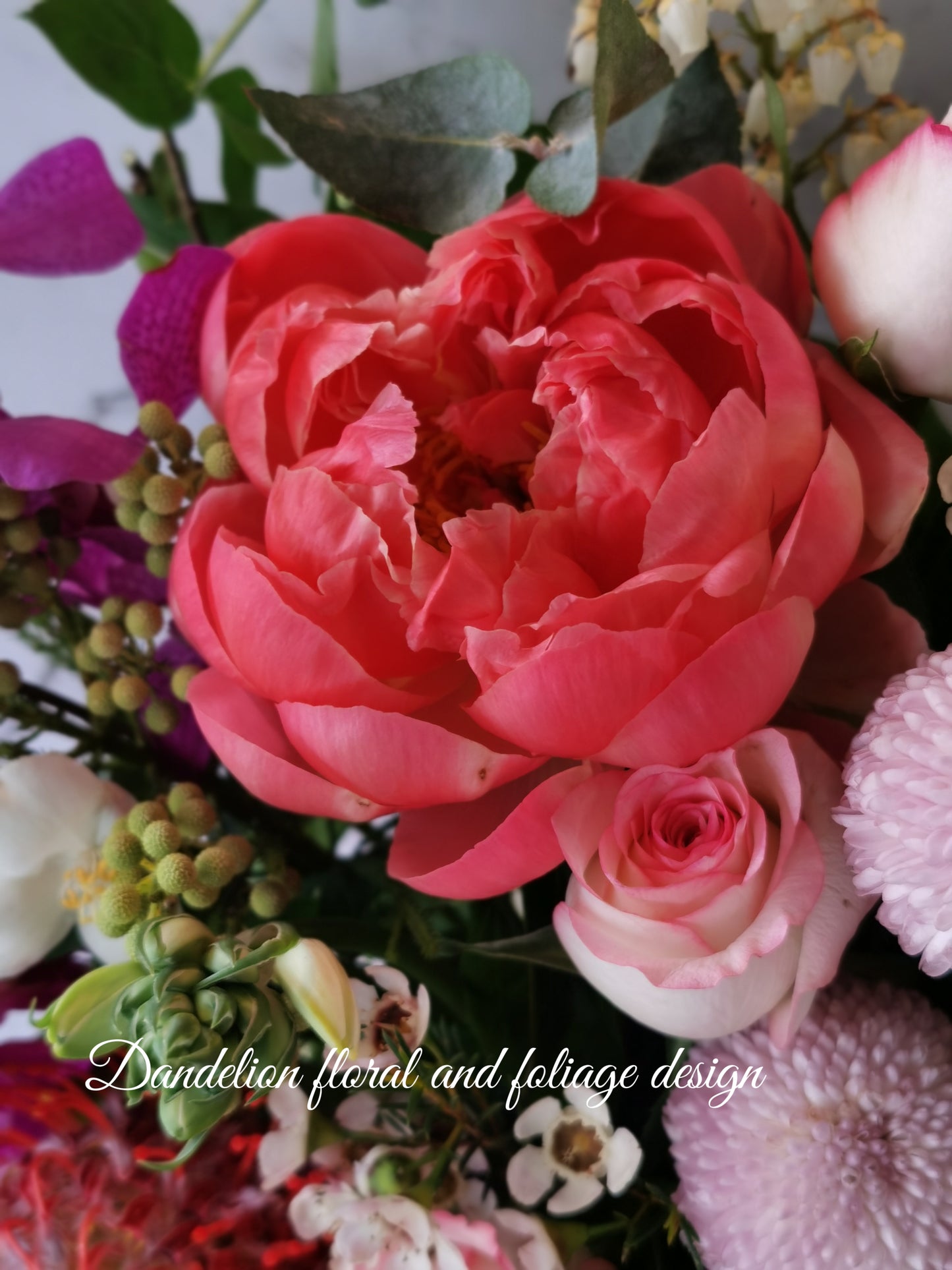 A floral arrangement featuring a variety of flowers including pink roses, orchids, and other plants in a hat box. Whether you're celebrating birthdays, anniversaries, weddings, or extending sympathy and support, our flowers and gifts are crafted to resonate with the unique emotions of each moment. Our commitment to quality ensures that every floral arrangement and gift is an embodiment of your care and consideration, destined to leave an impression.