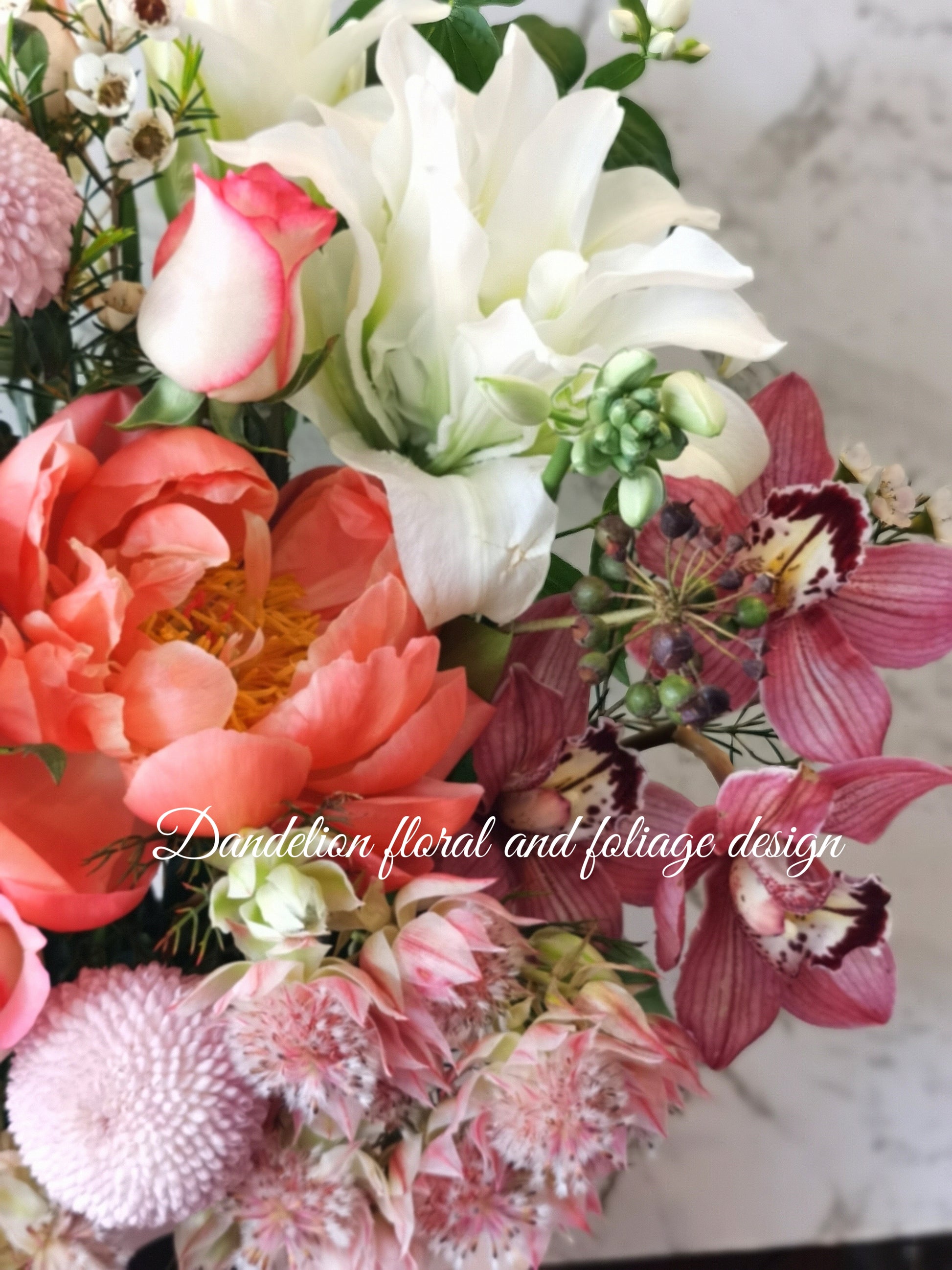 A floral arrangement featuring a variety of flowers including pink roses, orchids, and other plants in a hat box. Whether you're celebrating birthdays, anniversaries, weddings, or extending sympathy and support, our flowers and gifts are crafted to resonate with the unique emotions of each moment. Our commitment to quality ensures that every floral arrangement and gift is an embodiment of your care and consideration, destined to leave an impression.