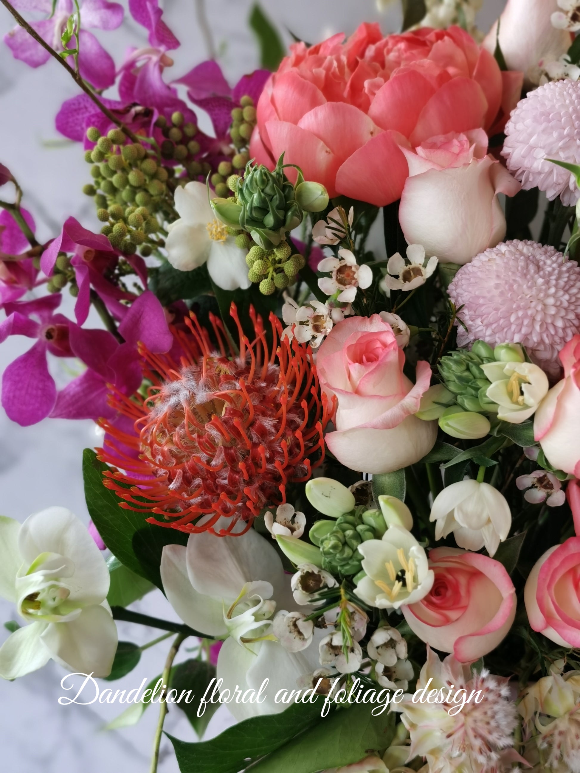 A floral arrangement featuring a variety of flowers including pink roses, orchids, and other plants in a hat box. Whether you're celebrating birthdays, anniversaries, weddings, or extending sympathy and support, our flowers and gifts are crafted to resonate with the unique emotions of each moment. Our commitment to quality ensures that every floral arrangement and gift is an embodiment of your care and consideration, destined to leave an impression.