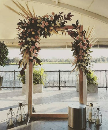 Decorative floral arch with candles on a patio overlooking water
