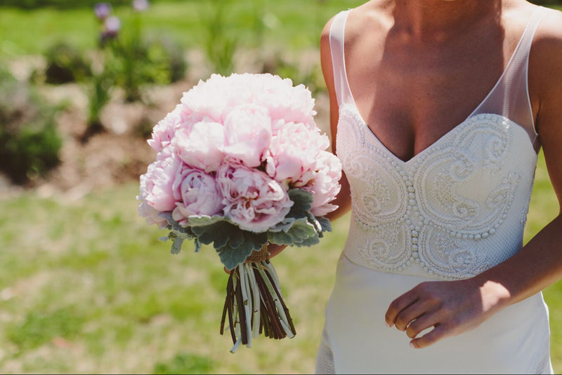 Bride holding a bouquet of pink flowers in an outdoor setting