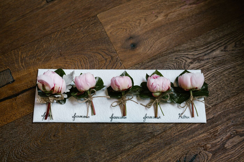 Set of pink flower boutonnieres on a wooden surface
