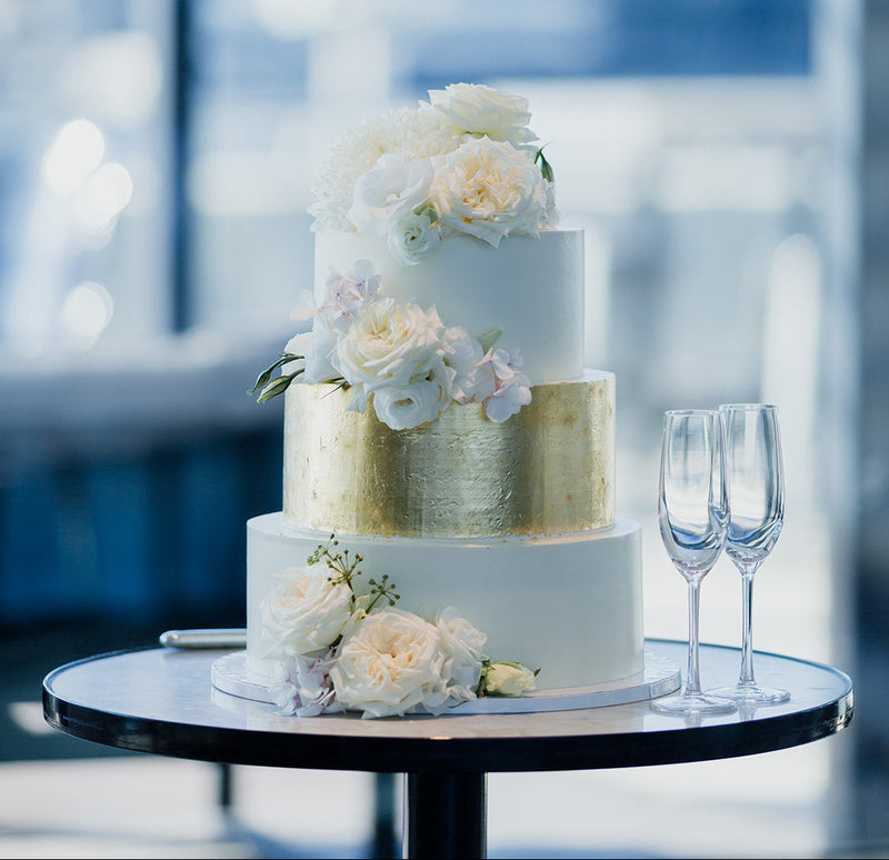 Three-tiered wedding cake with floral decorations on a table with a blurred background