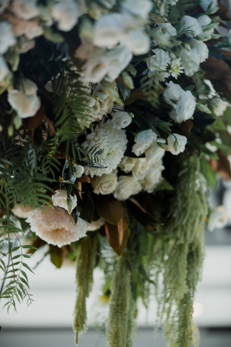 Close-up of a hanging floral arrangement with white flowers and greenery