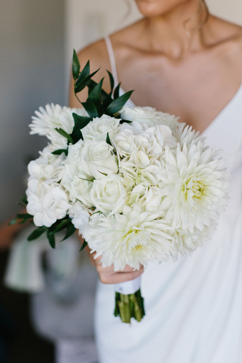 Bouquet of white flowers held by a bridal in a white dress for luxury wedding
