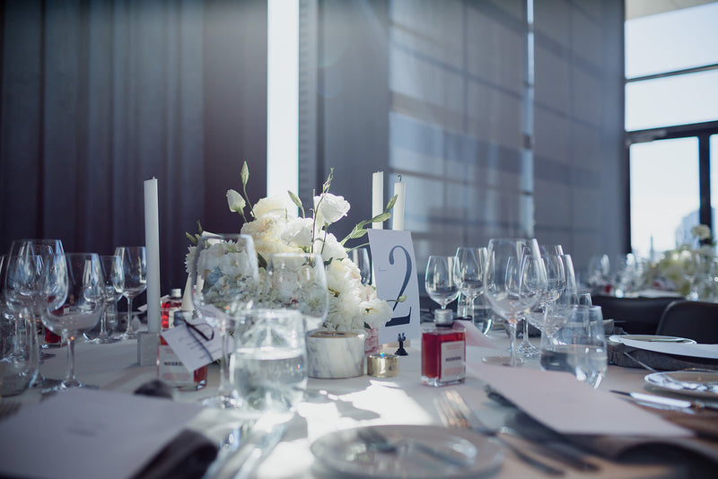 Elegant table setting with white and green floral centerpiece and wine glasses in a modern room.