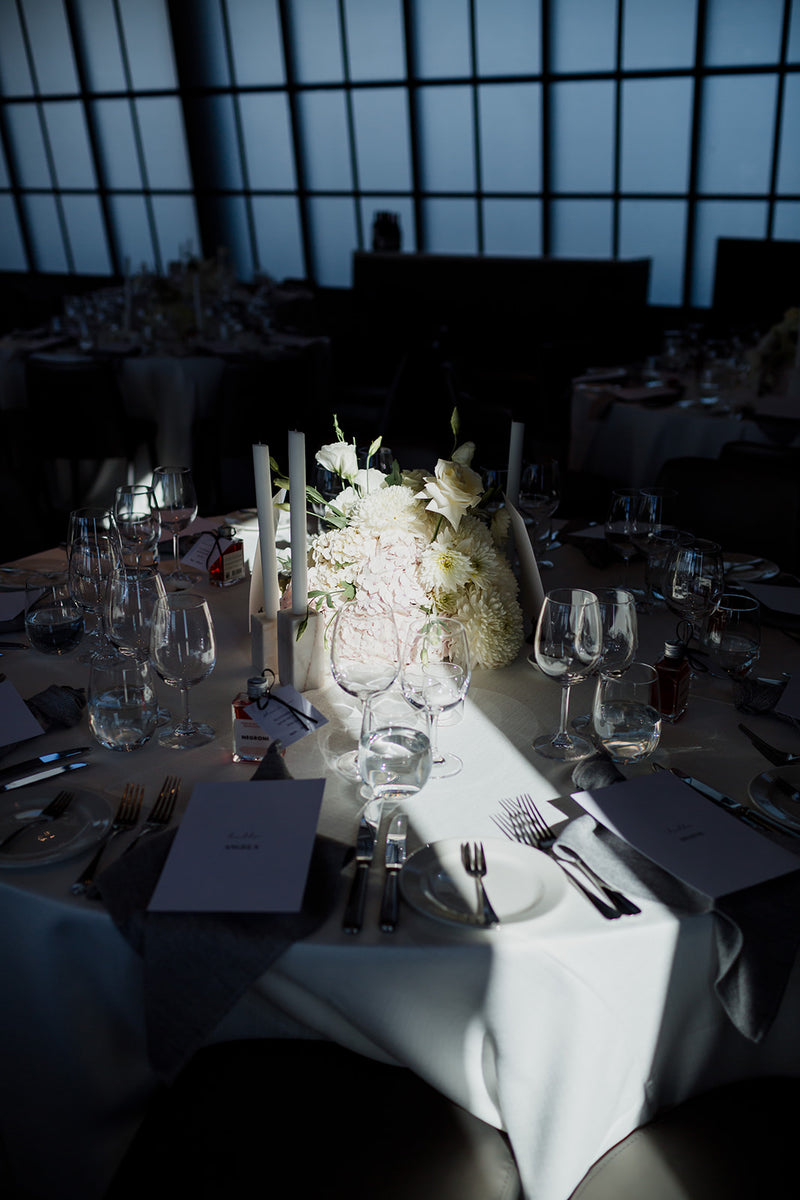 Elegant table setting with white and green floral centerpiece in a dimly lit room.