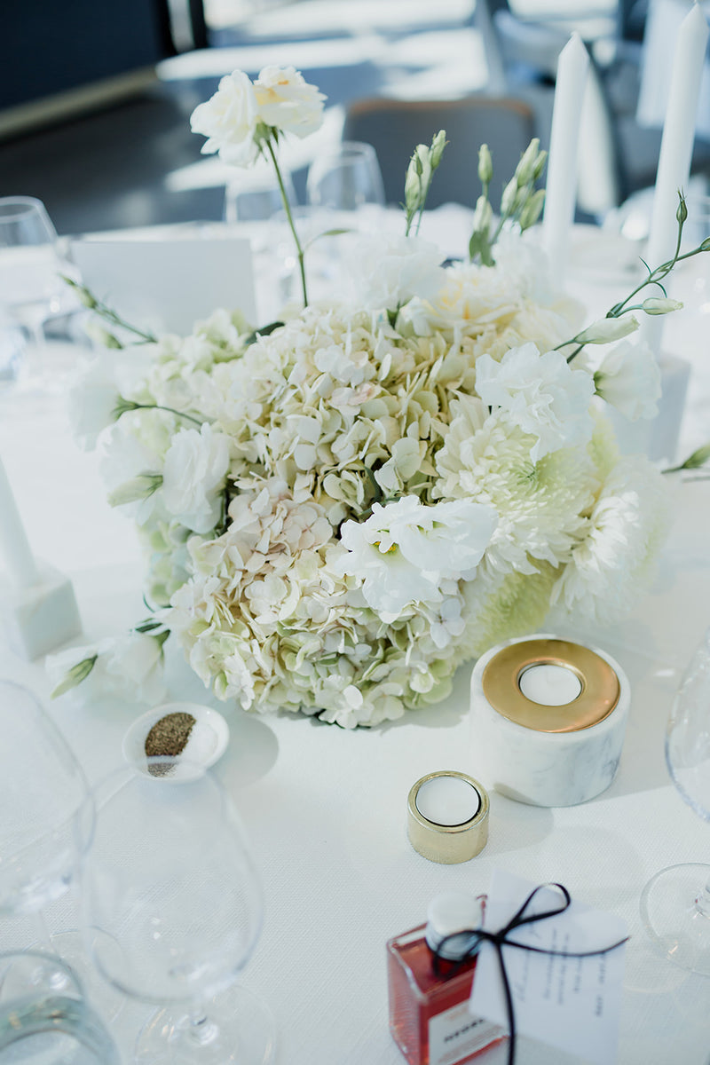 White floral arrangement on a table with candles and decorative items for wedding