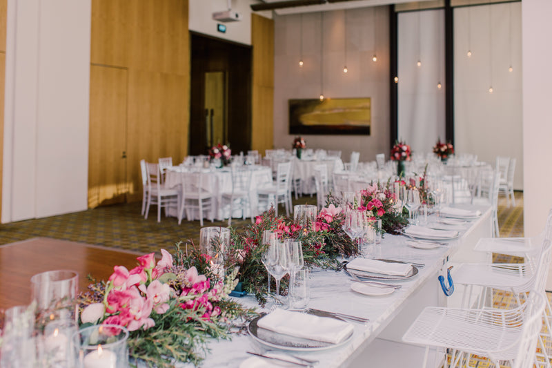 Decorated event table with floral arrangements in a large room. 