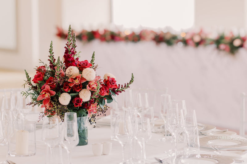 Decorative floral arrangement on a table with a blurred background of chairs and tables.