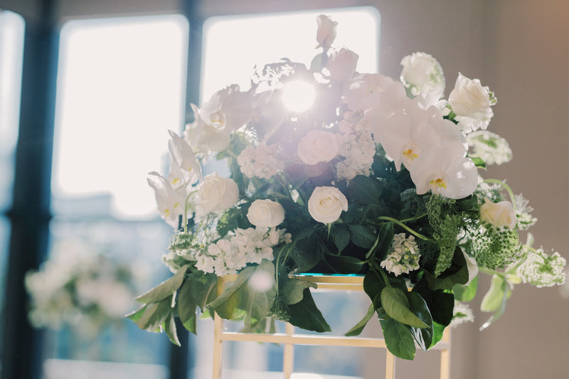 High end white and green floral arrangement on a chair with a blurred background for luxury wedding