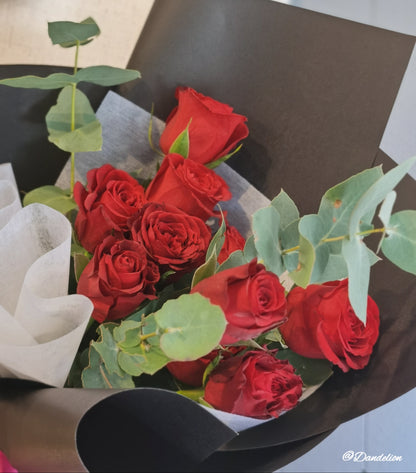 A bouquet of red roses with green foliage, wrapped in a black paper, 40cm premium red roses with seasonal foliage.
