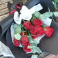A bouquet of red roses with green foliage, wrapped in a black paper, 40cm premium red roses with seasonal foliage.