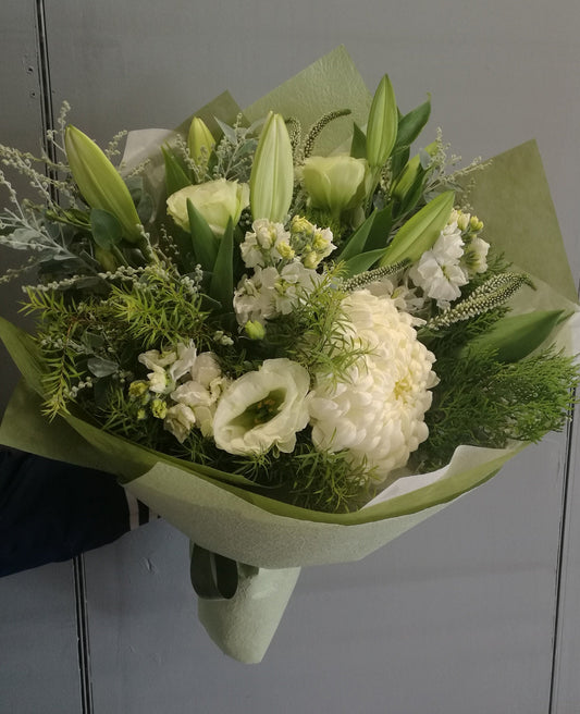 A bouquet of white and green flowers wrapped in green paper.