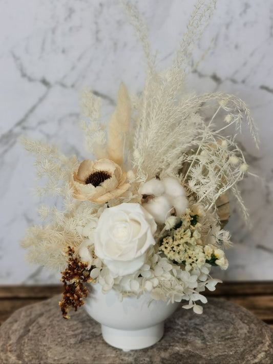 A floral mini arrangement in a white vase, featuring a mix of dried flowers including roses and other plants.